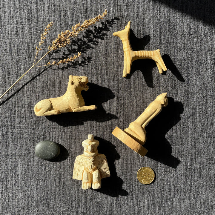 Top view of the Ancient Animal Guardian Set surrounded by vintage archaeological objects — handmade replicas of the Aztec Condor Warrior, Urartian Lion, Mycenaean Dog, and Calusa Marco Cat placed among old maps, stone fragments, and dried herbs. Artistic flatlay capturing ancient symbolism and boho aesthetic by ArkeoArt.
