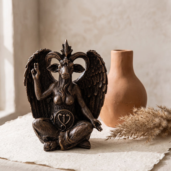 Baphomet Sculpture Replica styled on a vintage bookshelf surrounded by occult literature, aged leather-bound books, crystals, candlelight, and antique decorative objects. Inspired by timeless esoteric traditions, this handcrafted gothic statue enriches libraries, study rooms, and dark academia interiors while celebrating symbolic artistry. Museum-inspired craftsmanship by ArkeoArtDesign.