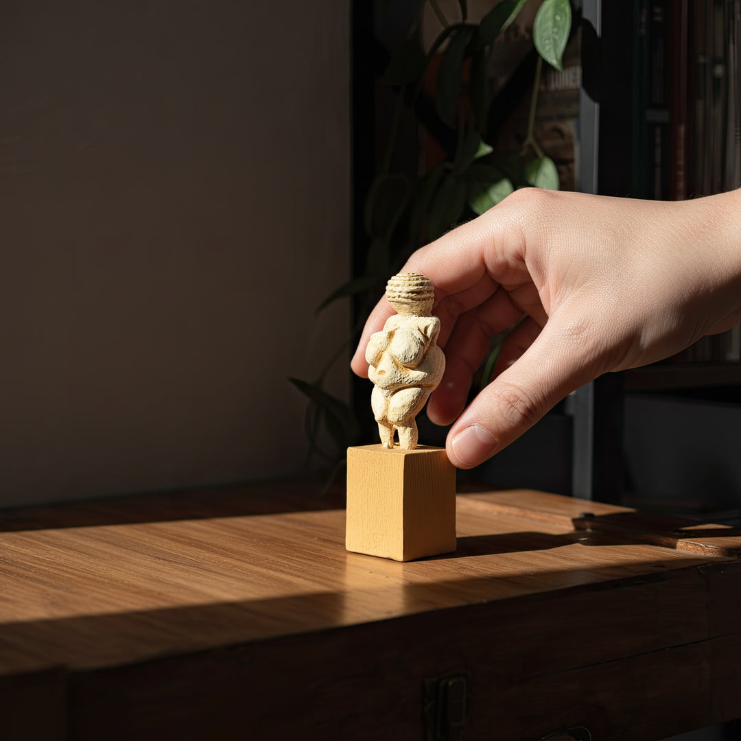 “Hand holding the Venus of Willendorf figurine for size reference — handmade miniature sculpture showing realistic proportions and tactile craftsmanship.”
(Türkçe)
“Boyut referansı için Willendorf Venüsü figürünü tutan el — gerçekçi oranlara sahip el yapımı minyatür heykel, dokunsal el işçiliğini gösterir.”