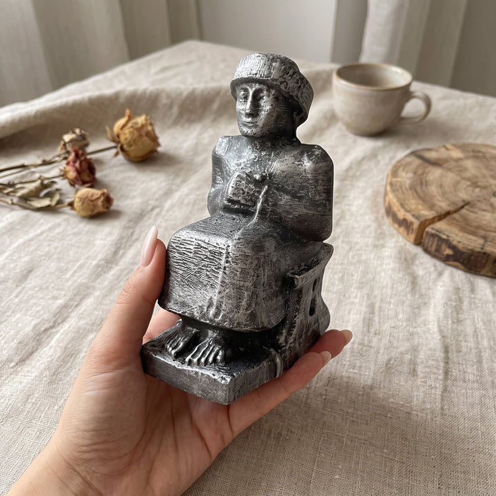 Kadın elinde tutularak ürünün gerçek boyutunu gösteren fotoğraf. Gudea Heykeli Replikası, tek elde rahatlıkla kavranabilecek ölçüleriyle diorit taş görünümünü, ince yüzey dokusunu ve üzerindeki karakteristik Sümer çivi yazısı detaylarını yakından sergiler. Lagaş Kralı Gudea'yı temsil eden bu Neo Sümer müze replikası; Antik Mezopotamya tarihi, arkeoloji ve koleksiyon dekorasyonu tutkunları için ArkeoArt el işçiliğiyle hazırlanmış seçkin bir sanat eseridir.
