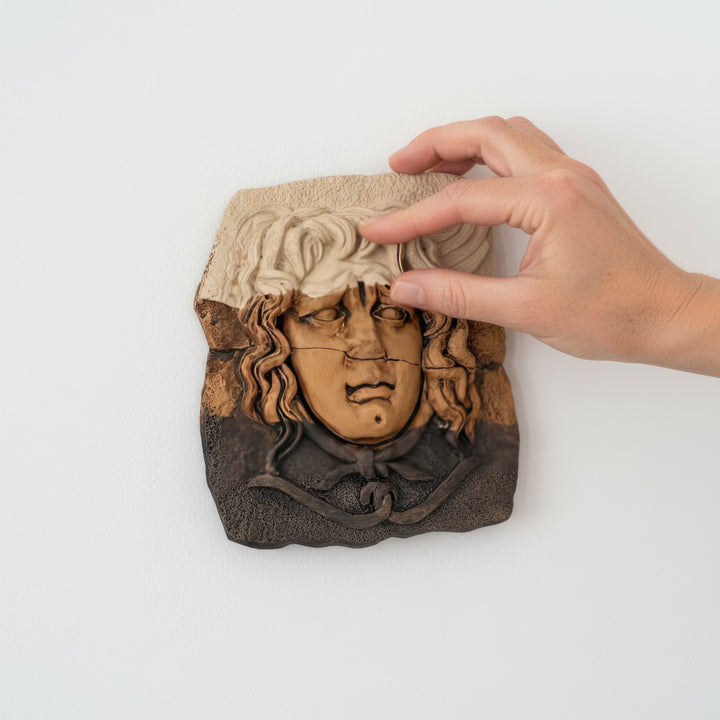 “Hand gently touching the handcrafted Medusa relief sculpture mounted on a white wall — demonstrating texture, size, and artisanal quality. A symbolic blend of Greek mythology and modern craftsmanship.”
TR:
“Beyaz duvara monte edilmiş el yapımı Medusa rölyefine nazikçe dokunan el — dokuyu, boyutu ve zanaatkâr kalitesini vurguluyor. Yunan mitolojisi ile modern el işçiliğinin simgesel birleşimi.”