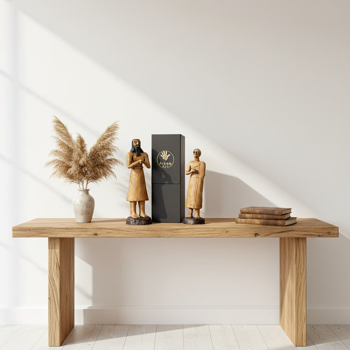 “Two Sumerian votive statues — the Priest-King and Priestess — placed side by side on a wooden table decorated with dried branches. A soft-toned archaeological display evoking ancient devotion and temple serenity.”
TR:
“Kuru dallarla dekore edilmiş ahşap masa üzerinde yan yana duran iki Sümer votif heykeli — Rahip-Kral ve Rahibe — antik adanmışlığı ve tapınak huzurunu çağrıştıran yumuşak tonlu bir arkeolojik düzenleme.”