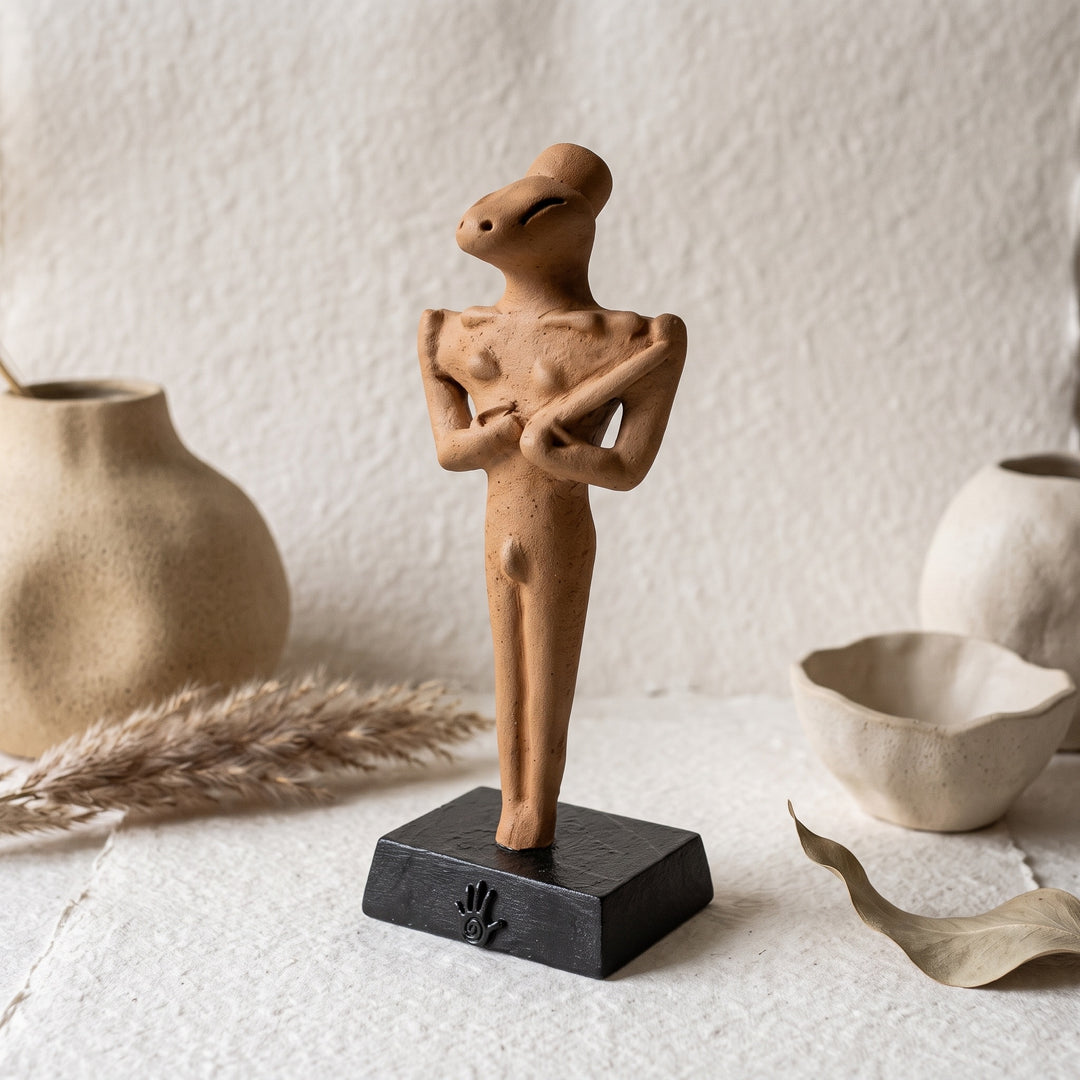 Minimalist ve boho dekorasyona sahip doğal tonlardaki bir rafta sergilenen Ubaid Ritüel Figürü, tarih öncesi Mezopotamya'nın en dikkat çekici arkeolojik buluntularından birini modern dekorasyon anlayışıyla buluşturur. İnce yüzey detayları ve karakteristik formuyla öne çıkan bu el yapımı figür; arkeoloji, antropoloji ve antik ritüel kültürleriyle ilgilenen koleksiyonerler için benzersiz bir dekoratif sanat eseridir. ArkeoArt tarafından hazırlanmıştır.