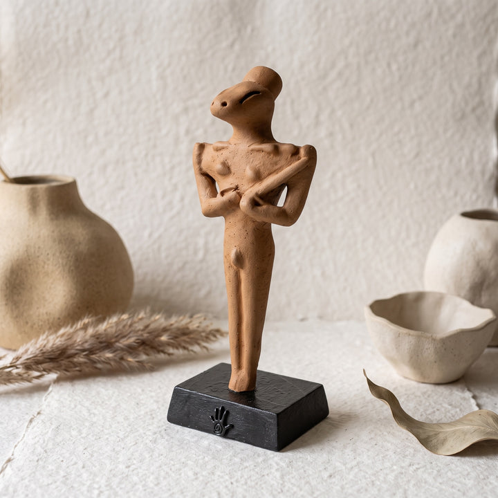 Minimalist ve boho dekorasyona sahip doğal tonlardaki bir rafta sergilenen Ubaid Ritüel Figürü, tarih öncesi Mezopotamya'nın en dikkat çekici arkeolojik buluntularından birini modern dekorasyon anlayışıyla buluşturur. İnce yüzey detayları ve karakteristik formuyla öne çıkan bu el yapımı figür; arkeoloji, antropoloji ve antik ritüel kültürleriyle ilgilenen koleksiyonerler için benzersiz bir dekoratif sanat eseridir. ArkeoArt tarafından hazırlanmıştır.