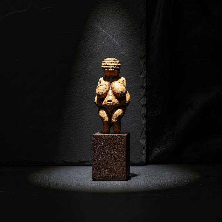 Willendorf Venüsü heykeli yukarıdan gelen yumuşak ışıkla çekilmiş Pinterest tarzı ürün fotoğrafı. Paleolitik doğurganlık tanrıçası figürü olan Venus of Willendorf replica, minimal masa dekoru içinde görülmektedir. ArkeoArt tarafından üretilen bu Paleolithic Venus statue, tarih öncesi sanat ve arkeoloji koleksiyonları için estetik ve kültürel bir dekoratif objedir.